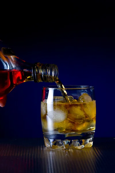 Whiskey into a glass with ice — Stock Photo, Image