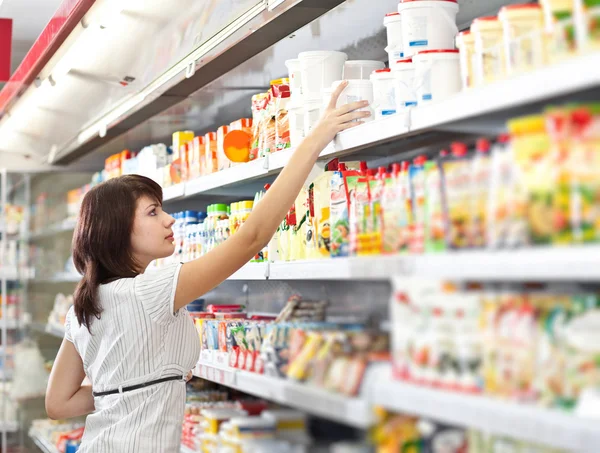 Mulher no supermercado escolhe comida — Fotografia de Stock