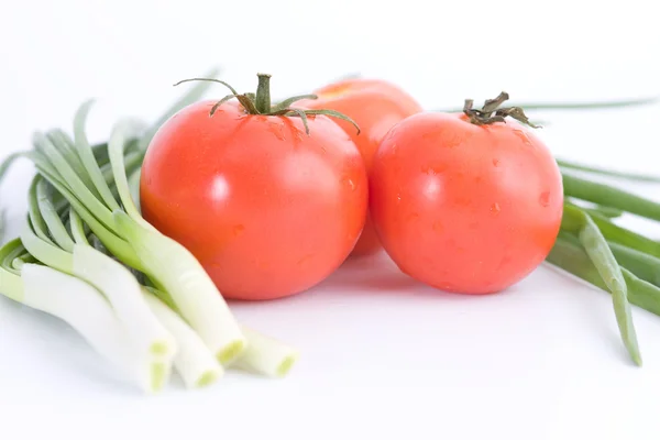 Tres tomates rojos y cebollas verdes —  Fotos de Stock