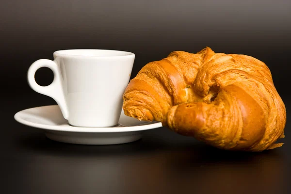 Café blanco taza y croissant en negro — Foto de Stock