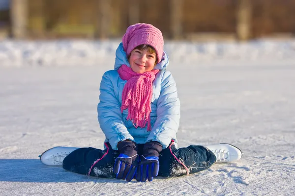 Girl on skates sitting on the ice. — Stock Photo, Image