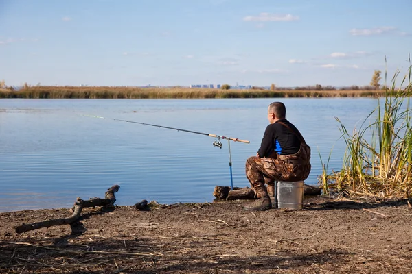 Pescatore seduto con attrezzatura da pesca — Foto Stock