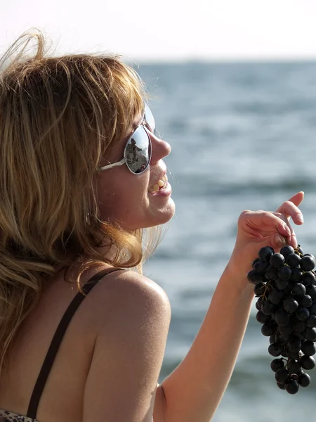 Женщина с виноградом на пляже — стоковое фото