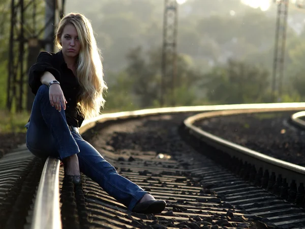 Молода жінка сидить на рейці — стокове фото