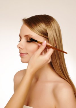 Pretty woman applying make up. clipart