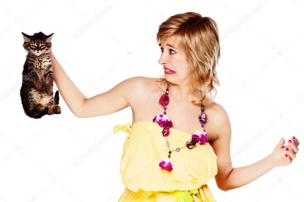 Young woman holding a kitten in disgust