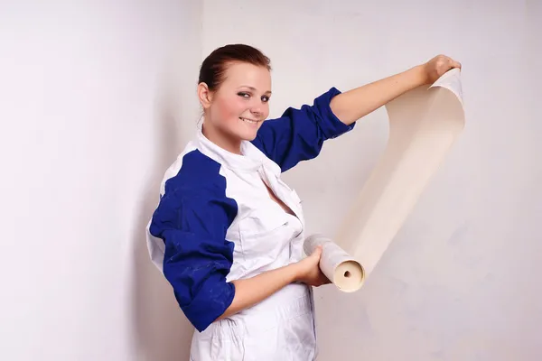 Молода жінка приміряє шпалери до стіни — стокове фото