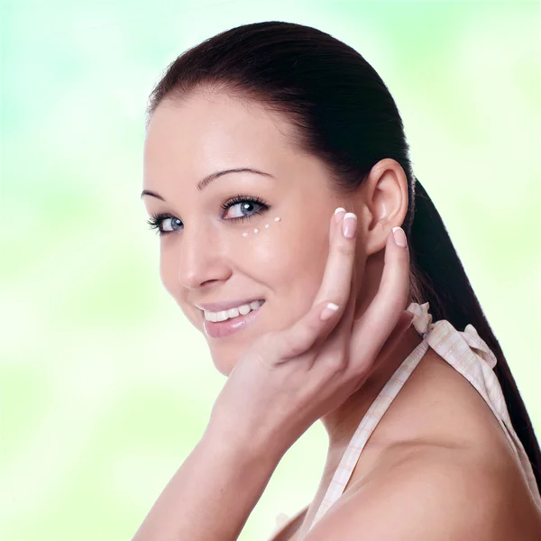 顔にクリームを適用する若い女性 — ストック写真