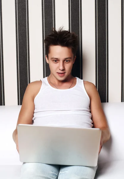 Молодой улыбающийся человек работает с ноутбуком — стоковое фото