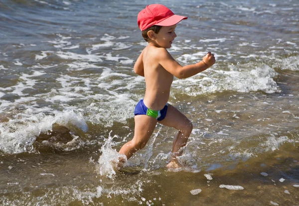 Glücklicher Junge, der im Wasser läuft — Stockfoto