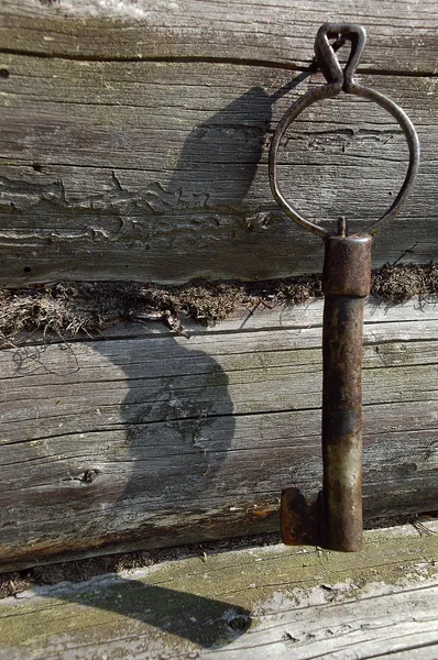 Vieille clé forgée sur le mur de la maison en bois rond — Photo