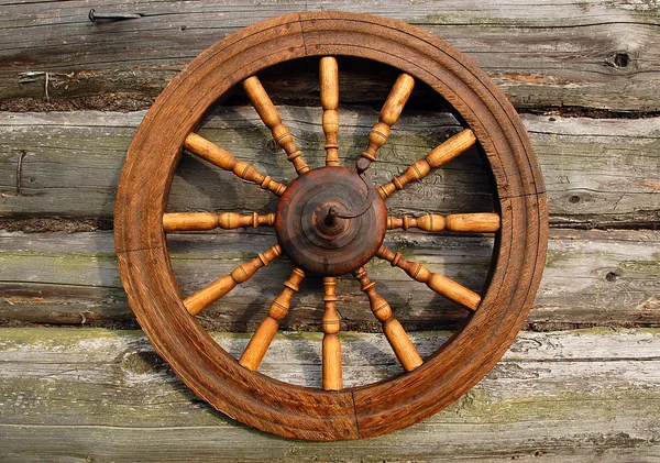 Крутящееся колесо на стене бревенчатого дома — стоковое фото