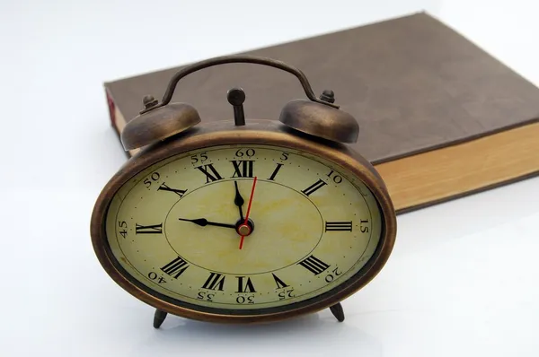 Старые часы и книга — стоковое фото