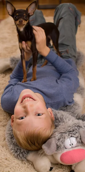 Trevlig unge med en leksak och en liten hund — Stockfoto