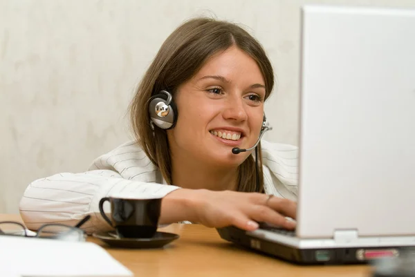 Chica joven con un ordenador portátil, auriculares y un — Foto de Stock