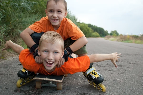 As crianças montam um skate na natureza — Fotografia de Stock