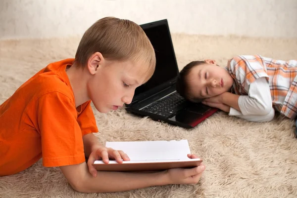 Ein Kind liest, während das andere schläft — Stockfoto