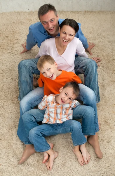 Família de quatro pessoas sentadas no tapete — Fotografia de Stock