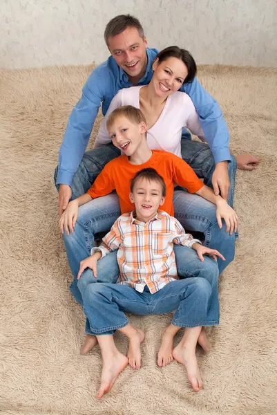 Familjen sitter på en vit matta — Stockfoto