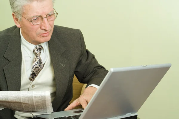 Old businessman sitting at a table — Stock Photo, Image