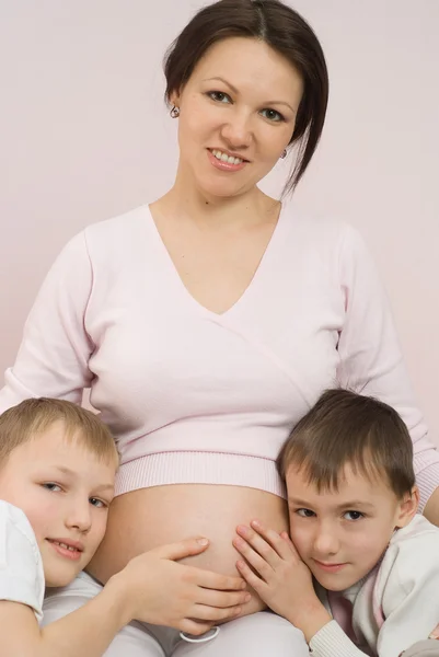Беременная женщина обнимает двоих детей — стоковое фото
