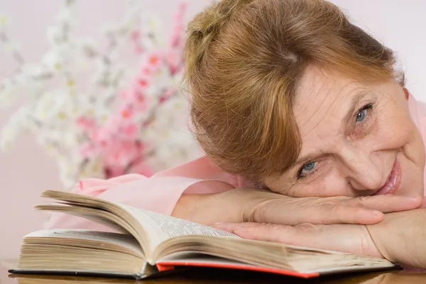 Mujer mayor leyendo un libro y sueños — Foto de Stock