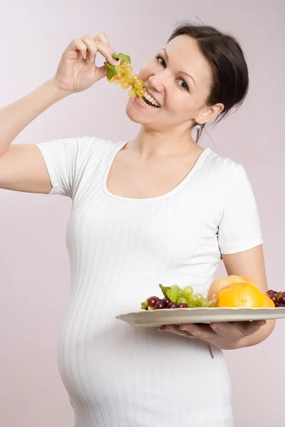 Женщина стоит и ест фрукты — стоковое фото