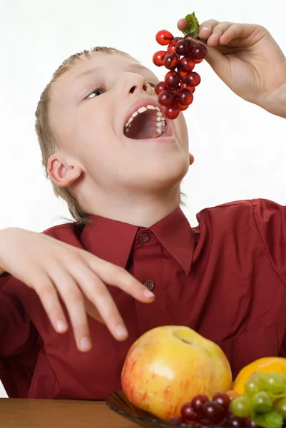 Menino de camisa vermelha comendo uvas — Fotografia de Stock