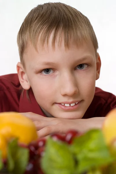 Chłopiec siedzi i patrzy na owoce — Zdjęcie stockowe