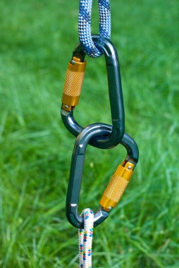 Carabiners on a green grass background clipart