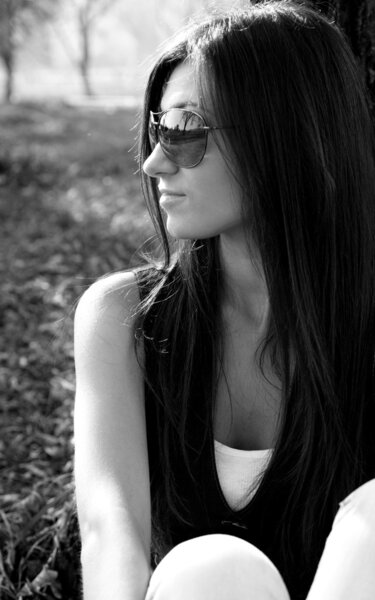 Beautiful young woman in dark glasses in park. black-and-white image