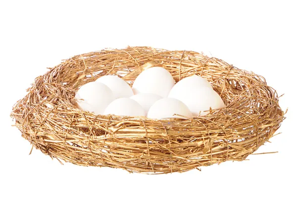 Белые яйца в золотом гнезде — стоковое фото
