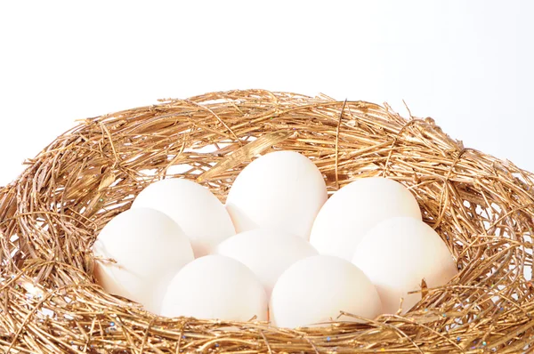 Белые яйца в золотом гнезде — стоковое фото