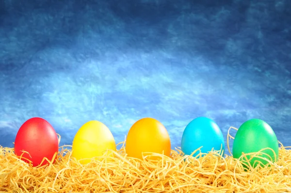 Five painted eggs on a straw on a sky ba — Stock Photo, Image