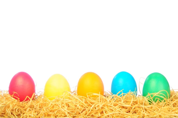 Cinco huevos pintados sobre una paja sobre un blanco — Foto de Stock