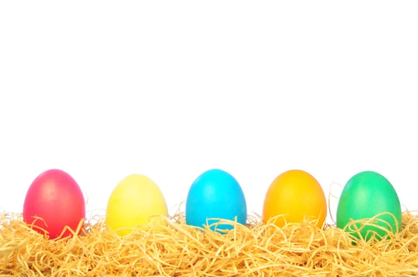 Cinco huevos pintados sobre una paja sobre un blanco — Foto de Stock