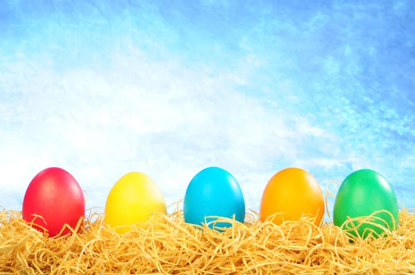 Cinco ovos pintados em uma palha em um céu ba — Fotografia de Stock