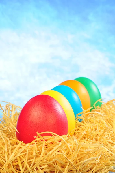 Five painted eggs in straw on a sky back — Stock Photo, Image