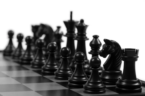 Schwarze Schachfiguren auf einem Schachbrett lizenzfreie Stockfotos