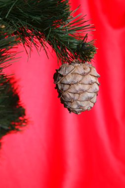 Christmas tree and cone against red back clipart