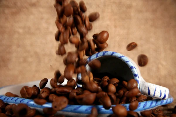 Copo, prato e grãos de café em queda — Fotografia de Stock