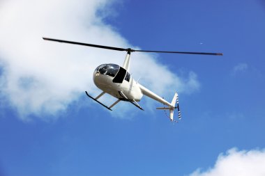Mavi gökyüzünde uçan helikopter.
