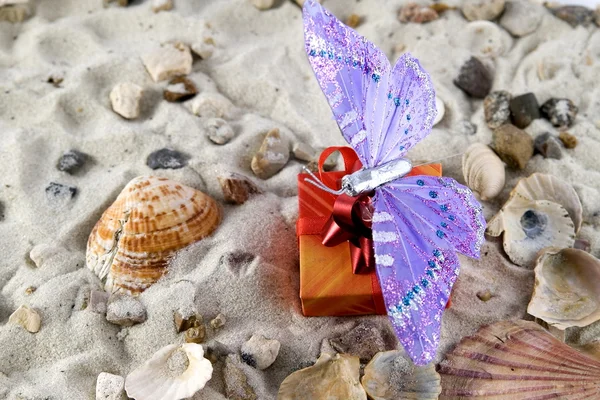 Gift and butterfly in the sand — Stock Photo, Image
