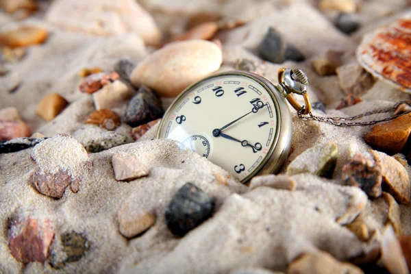 Vintage-Uhr im Sand mit Muschel Stockbild