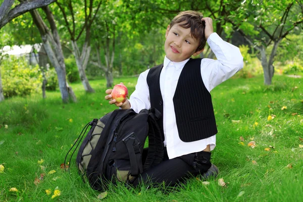 Думающий школьник с яблоком — стоковое фото
