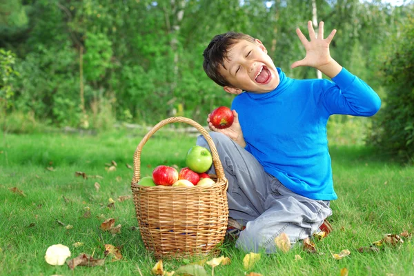 Liten pojke poserar med äpplen — Stockfoto