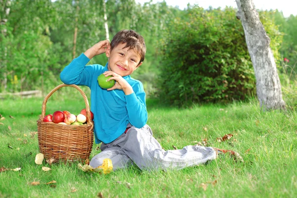 Malý kluk, venku pózuje s jablky — Stock fotografie