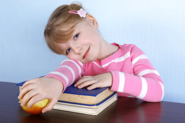 Liten flicka med äpple och böcker — Stockfoto