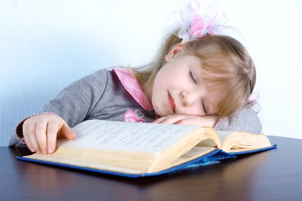 Flicka sover på boken på bordet — Stockfoto