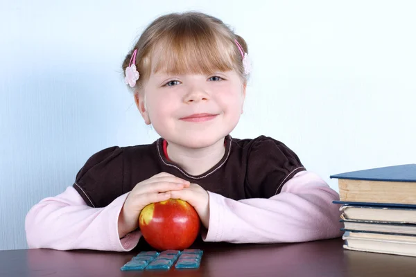 Маленька дівчинка з яблуком і книгами — стокове фото